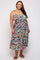 woman wearing a floral print plus size sundress with a square neckline and tiered skirt, standing with one hand on her hip