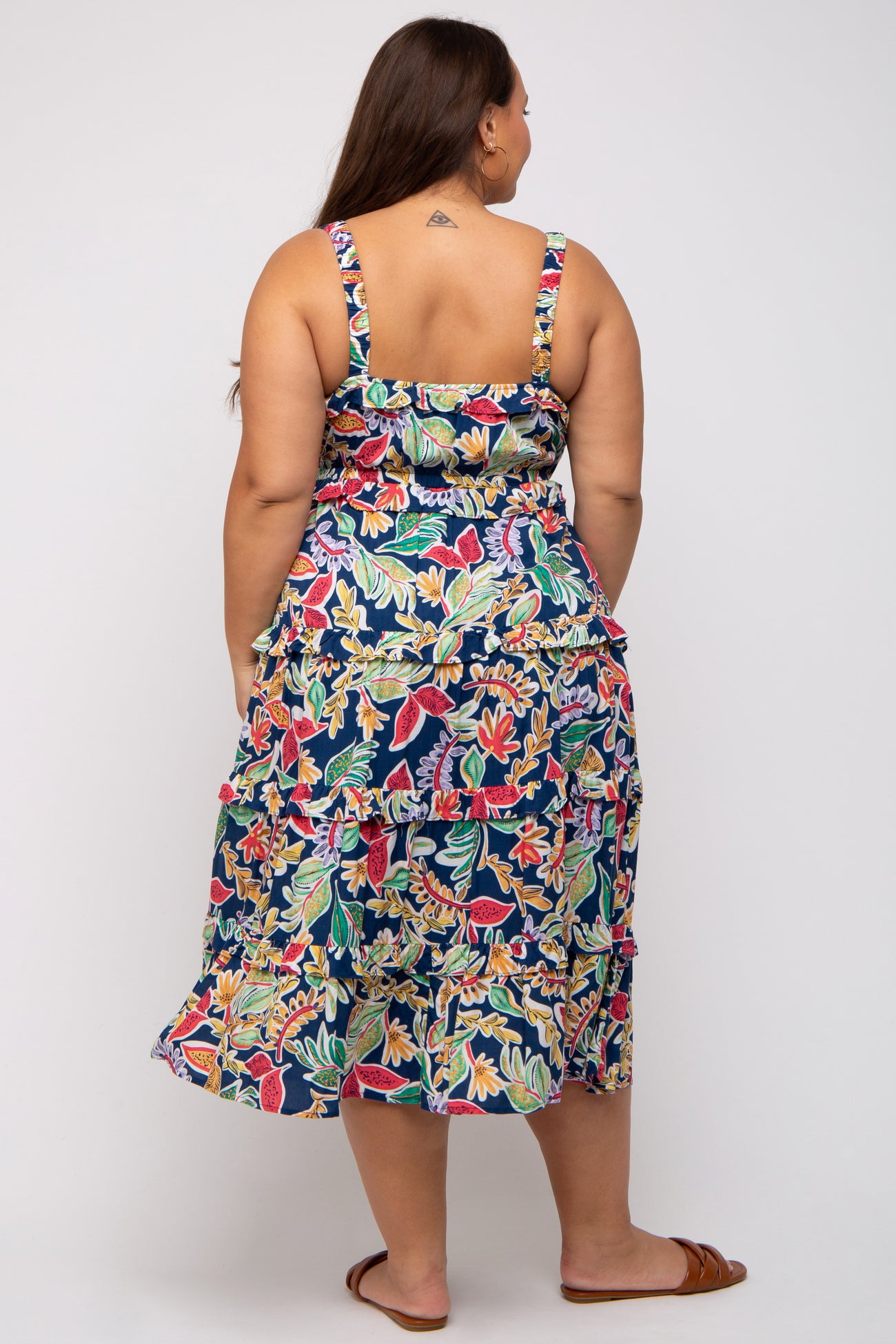 plus size woman wearing a colorful floral midi dress with ruffle details and adjustable straps, seen from the back