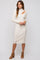 woman wearing a cream ribbed midi dress with long sleeves and a cut-out detail on the shoulder