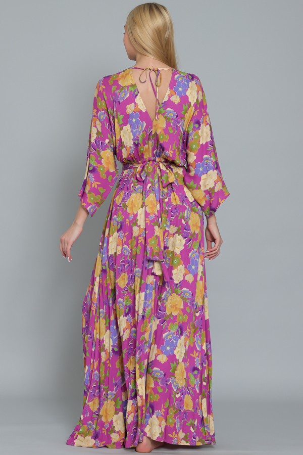 woman wearing a purple floral maxi dress with bell sleeves and a tied back detail