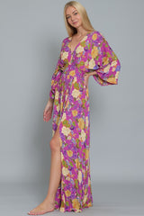 woman wearing a purple floral maxi dress with balloon sleeves and a high slit