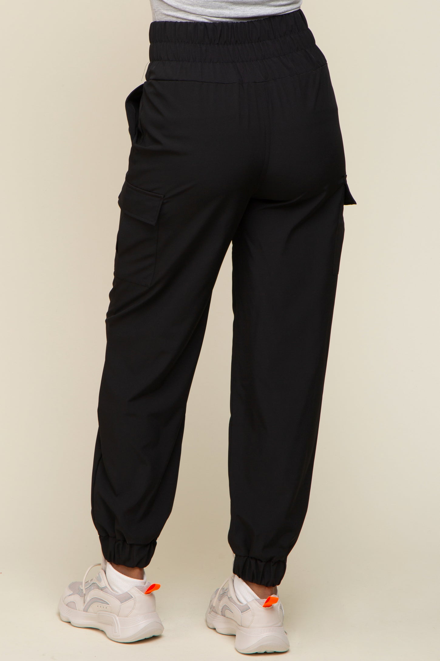 woman wearing black cargo pants with elastic waistband and ankle cuffs, shown from the back