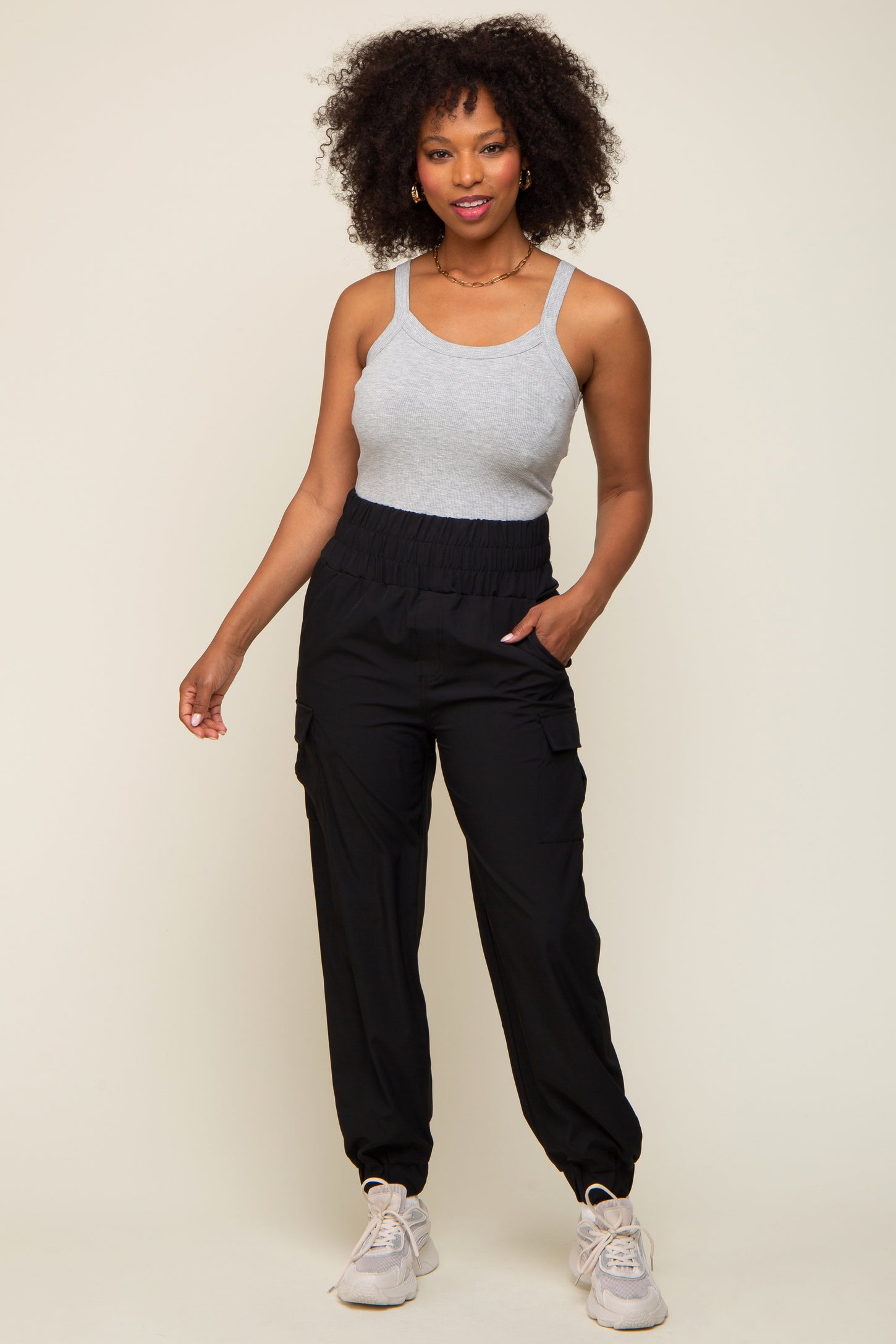 woman wearing a gray tank top and black cargo pants with an elastic waistband, standing confidently