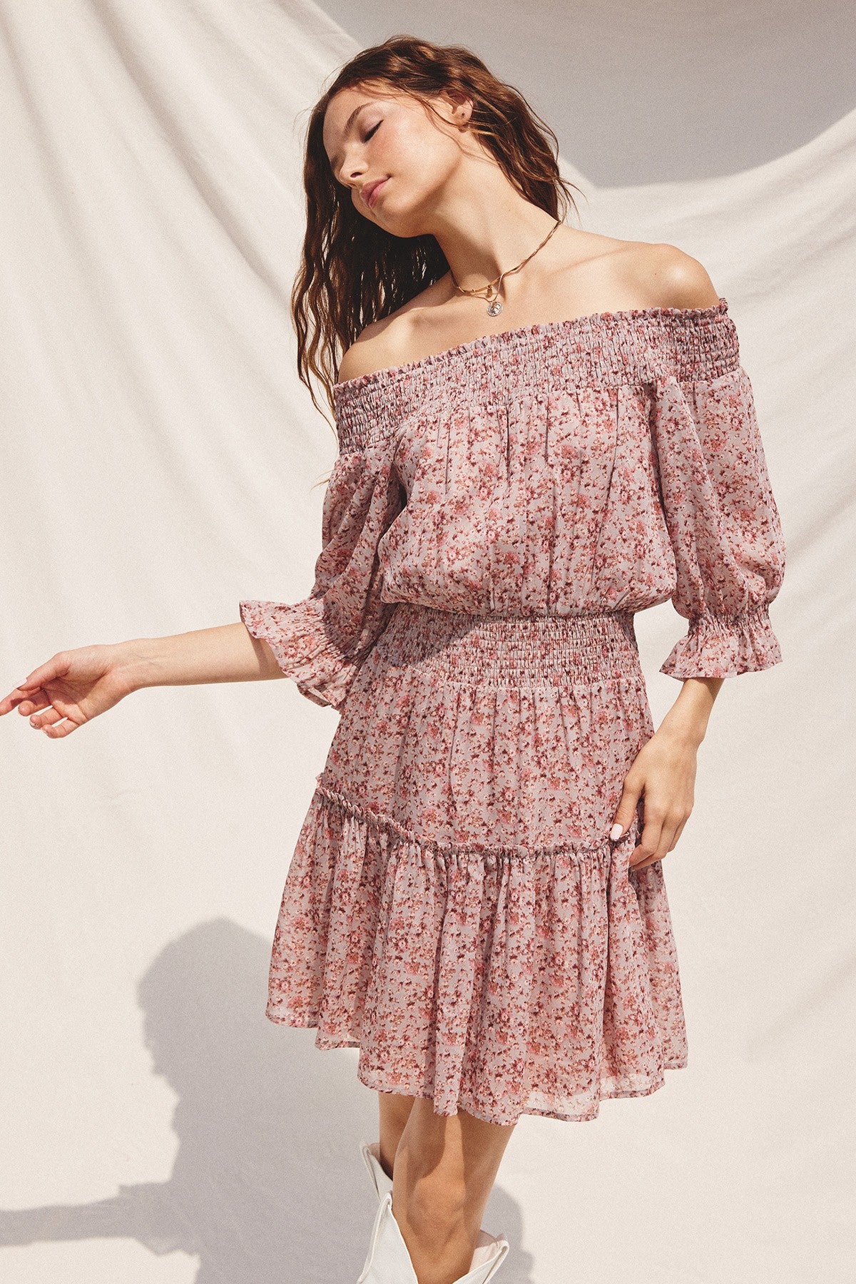 woman wearing a pink floral off-the-shoulder dress with puff sleeves and a smocked waist