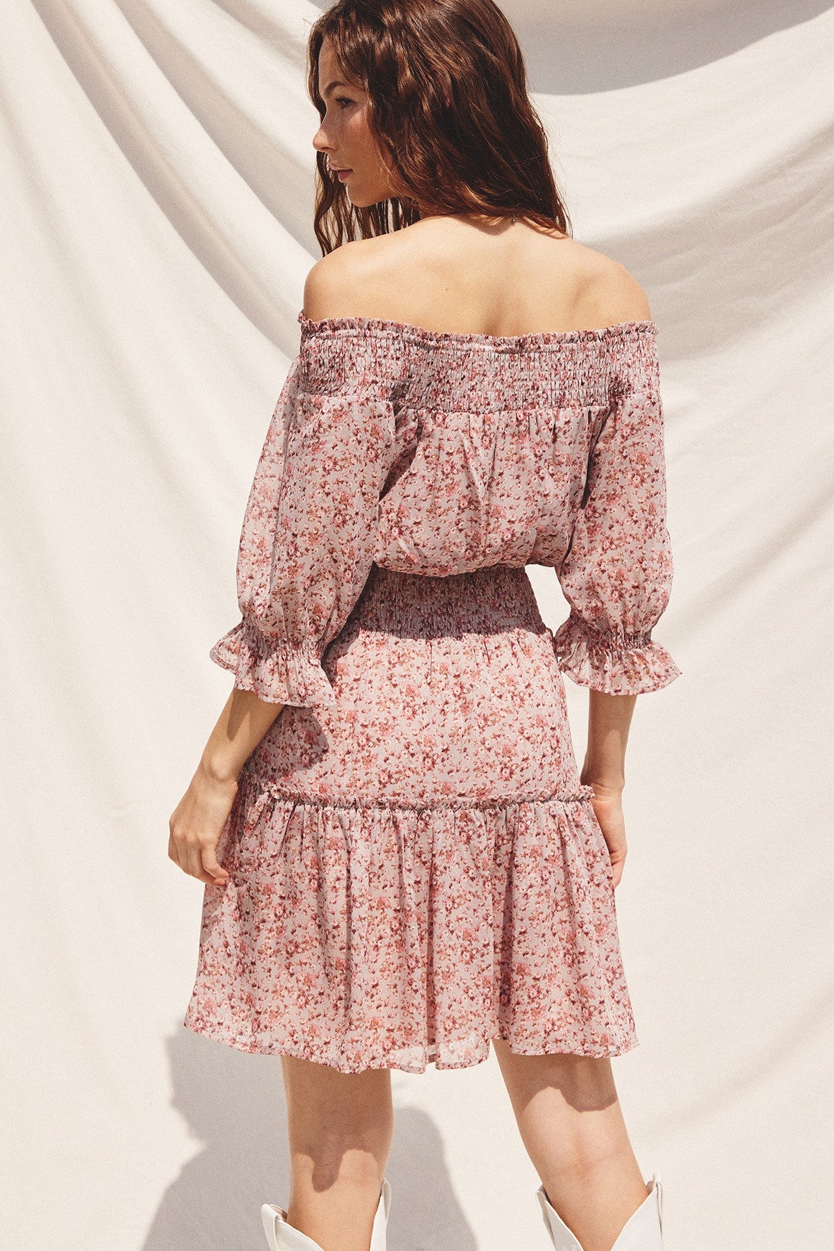 woman wearing a pink floral off-the-shoulder dress with ruffled sleeves and a tiered hem