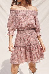 woman wearing a pink off-the-shoulder floral dress with puff sleeves and a smocked waist, styled with a flared skirt