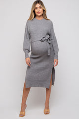 woman wearing a gray ribbed maternity dress with a tie waist and side slit, showcasing her baby bump