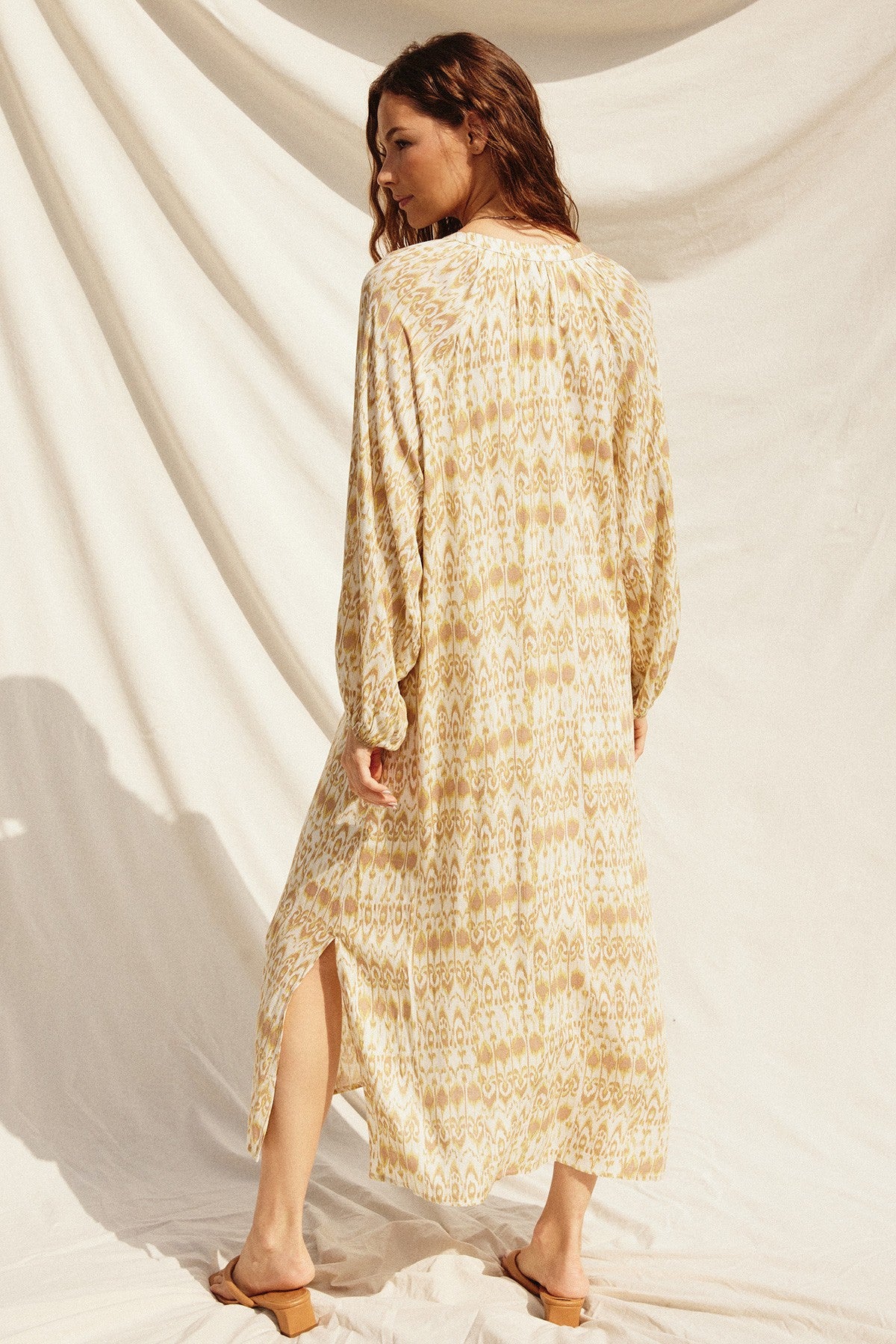 woman wearing a long sleeve tan and cream patterned maxi dress with side slits
