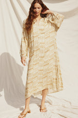 woman wearing a yellow and white patterned midi dress with long sleeves and a v-neckline