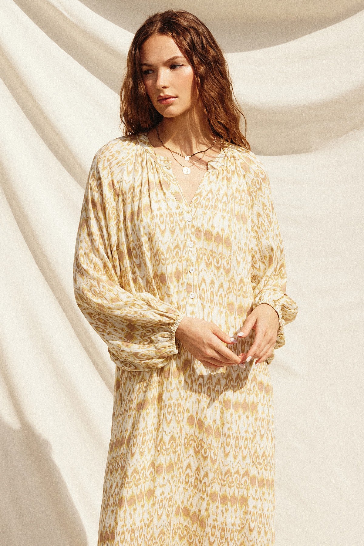 woman wearing a yellow and cream patterned long sleeve maxi dress with a v-neck and puffed sleeves