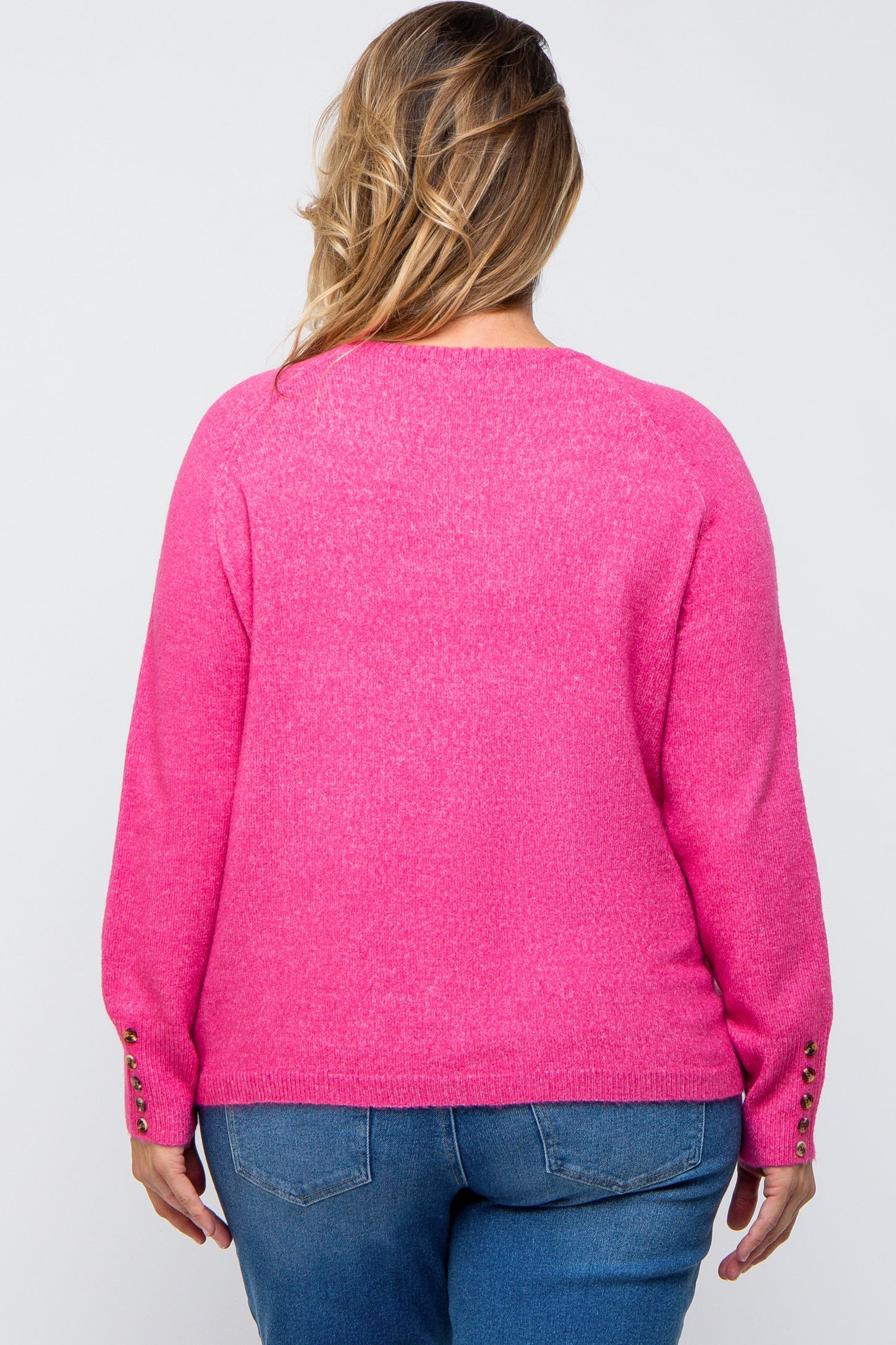 woman wearing a bright pink maternity plus sweater with button details on the sleeves, viewed from the back