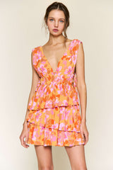 woman wearing a floral orange and pink tiered mini dress with a deep v-neckline and sleeveless design