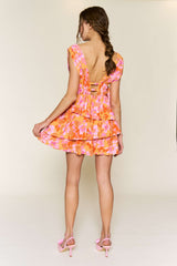 woman wearing a pink and orange floral tiered mini dress with a deep back and braided hairstyle