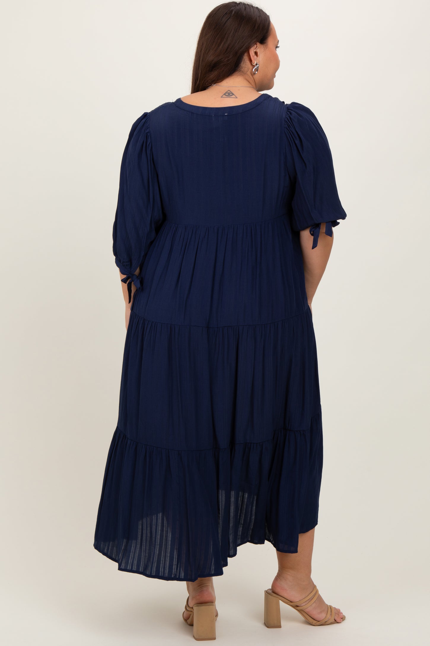 woman wearing a navy blue plus size maxi dress with puff sleeves and tiered ruffle detailing from the back