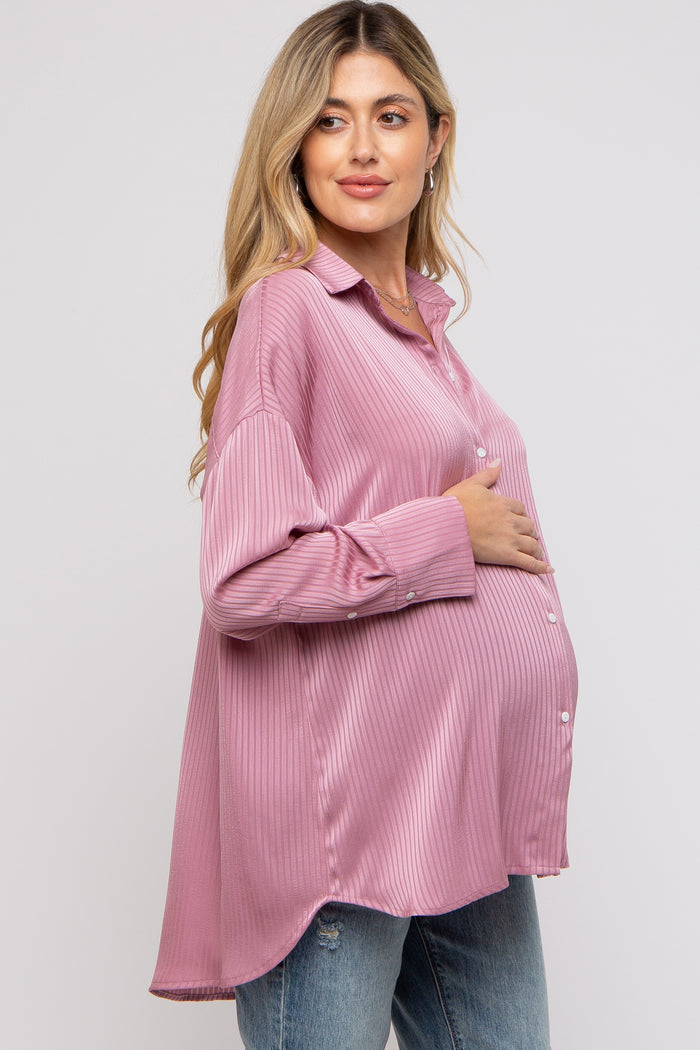 woman wearing a pink striped maternity button-up shirt and holding her baby bump