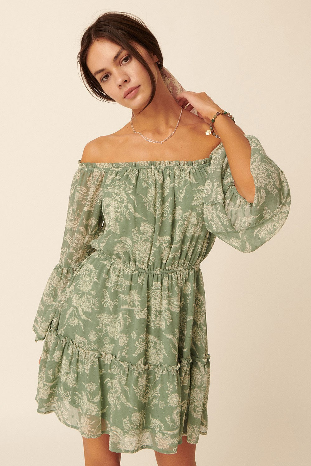 woman wearing a green off-the-shoulder floral print dress with puffed sleeves and tiered ruffles