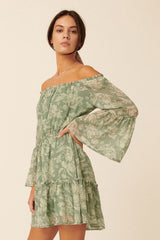 woman wearing a green floral off-the-shoulder mini dress with long bell sleeves