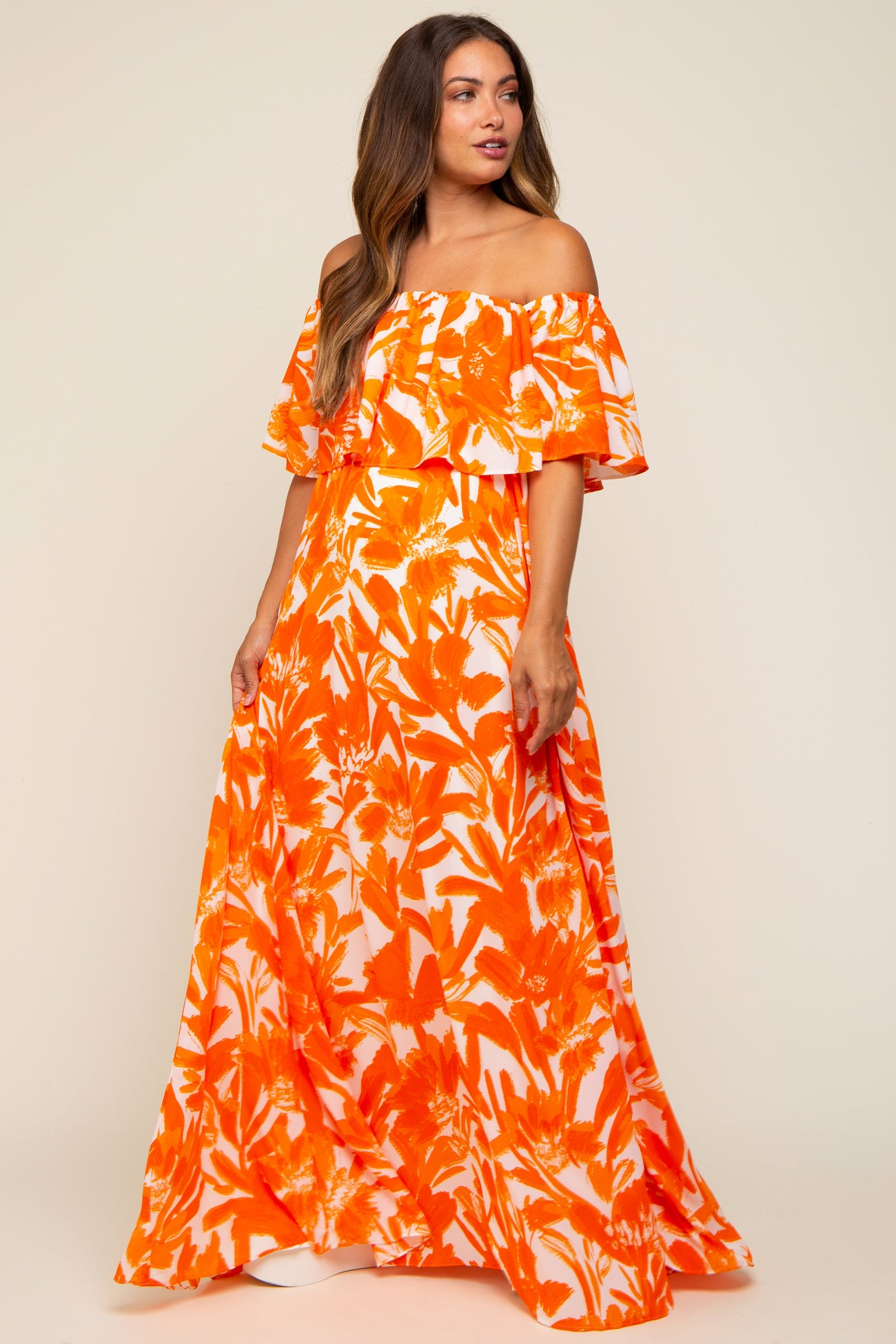 woman wearing an off-shoulder orange floral maxi dress, featuring ruffled sleeves, suitable for maternity wear