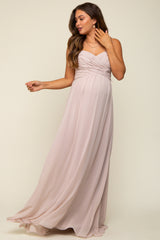 woman wearing a blush pink maternity maxi dress with a ruched bodice and flowing skirt, showcasing her baby bump