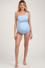 woman wearing a light blue one-shoulder maternity swimsuit with a cutout design and a visible baby bump
