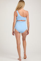 woman wearing a light blue one-shoulder maternity swimsuit with a cut-out detail at the back