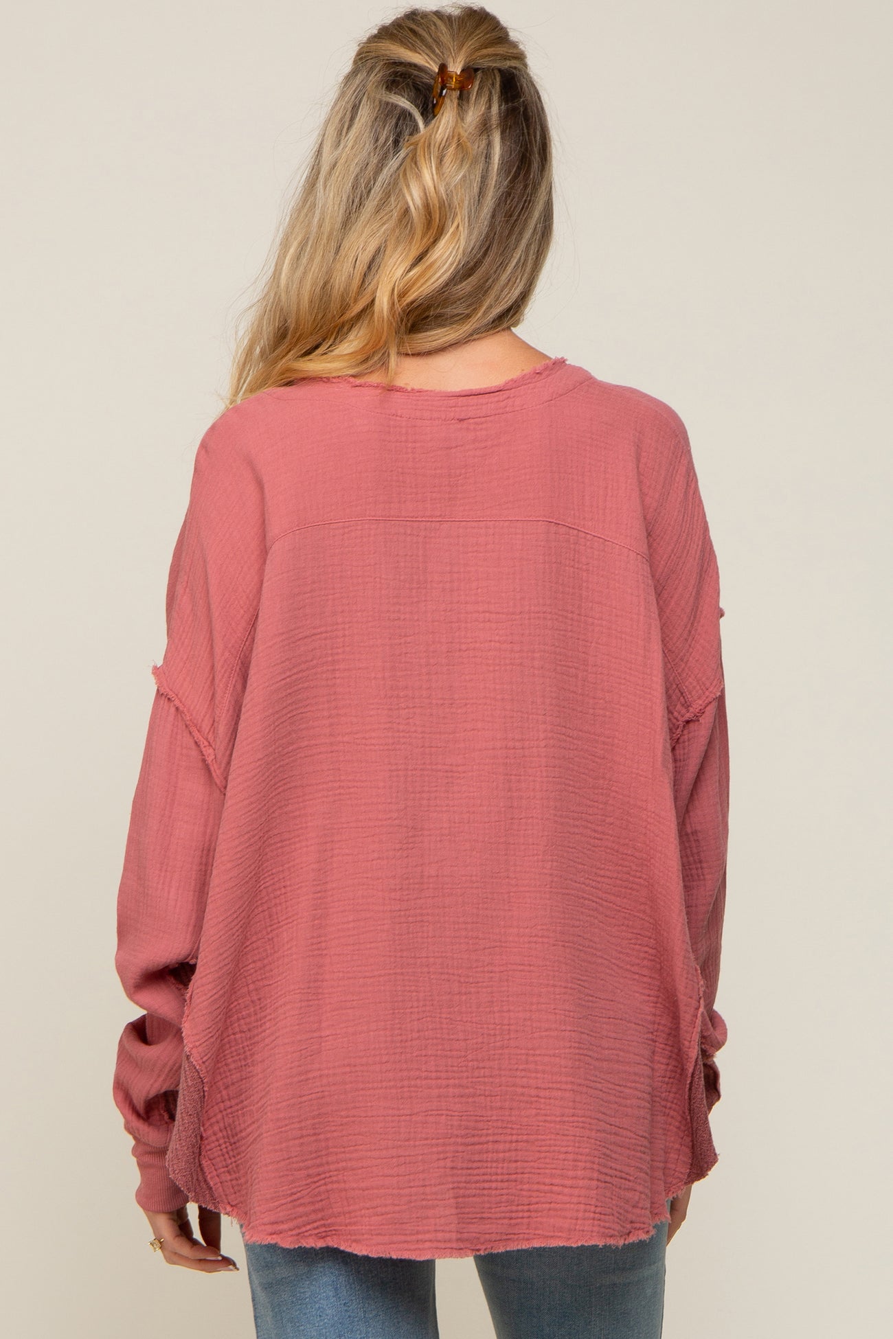 woman wearing a long sleeve dusty rose maternity top with a relaxed fit and frayed hem