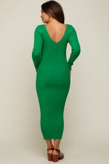 woman wearing a green ribbed maternity dress with a low back and long sleeves