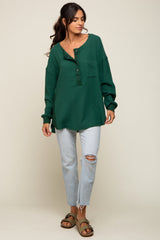 woman wearing a green waffle knit oversized henley shirt with buttons and a pocket, paired with light blue ripped jeans and sandals