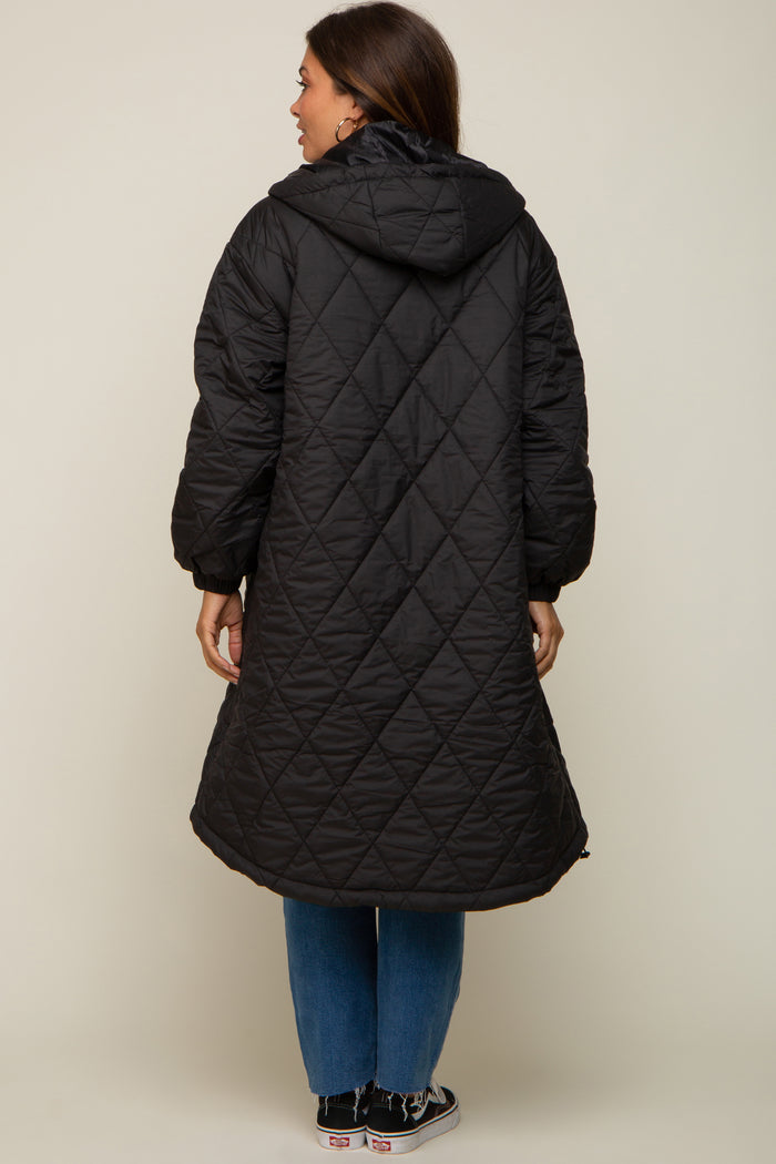 woman wearing a long black quilted maternity coat with a hood, seen from the back