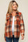 woman wearing an orange and brown plaid maternity shirt jacket over a white top with a visible baby bump