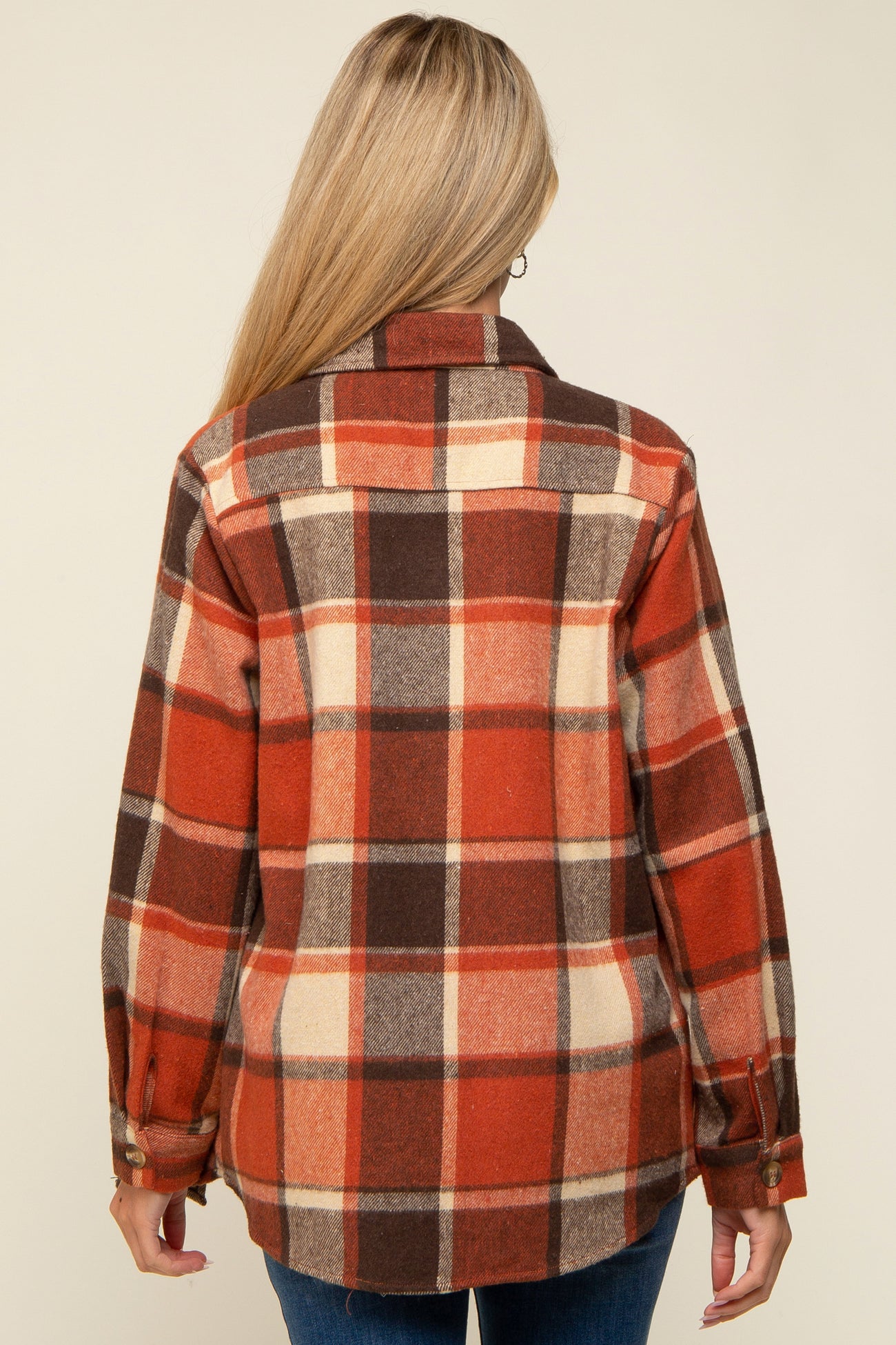 woman wearing a red, brown, and cream plaid maternity flannel shirt, shown from the back