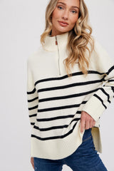 woman wearing a cream and black striped quarter-zip sweater with a relaxed fit and side slits