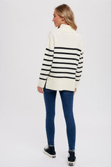 woman wearing a cream and black striped oversized sweater paired with skinny jeans and high-top sneakers, seen from the back