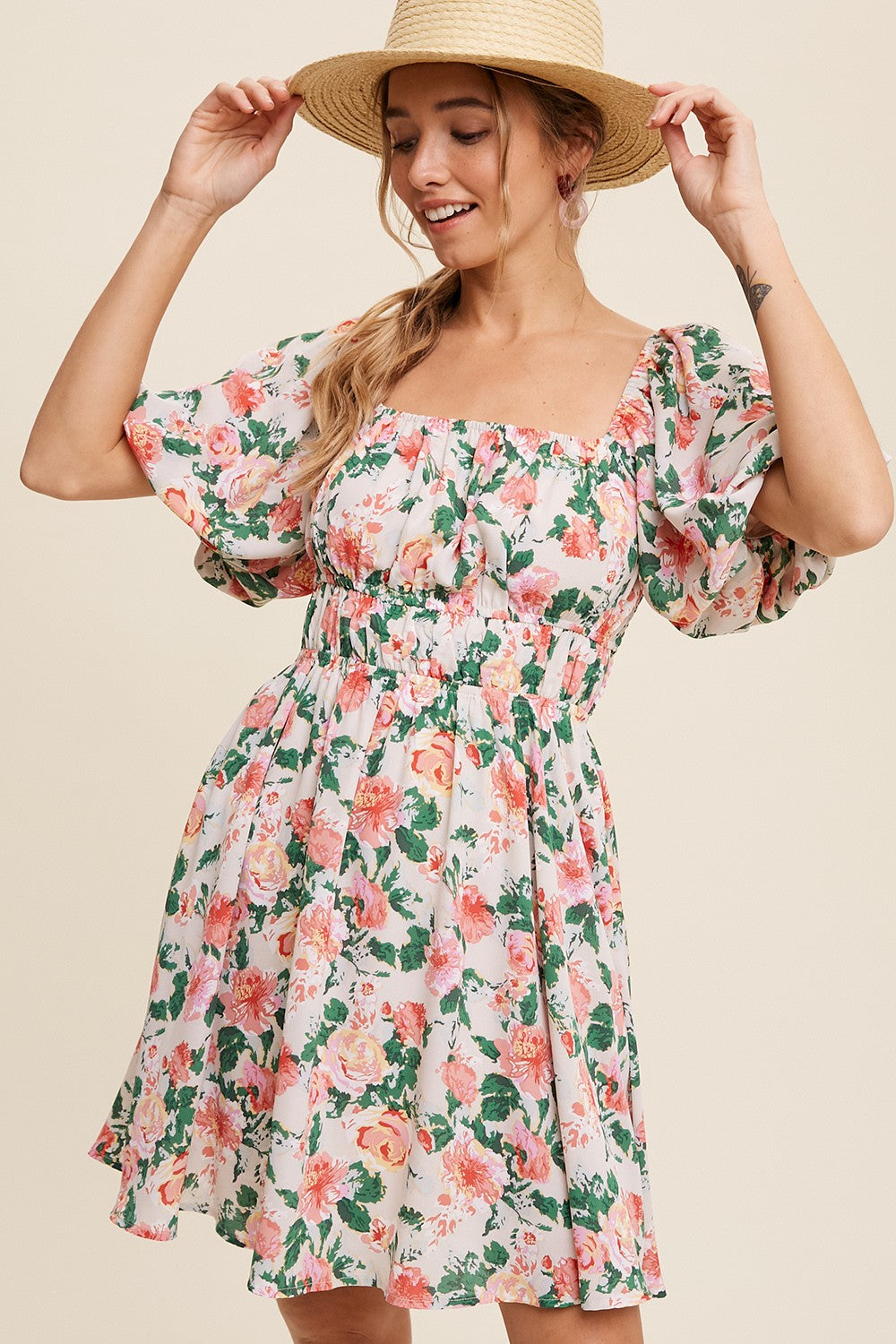 woman wearing a floral puff sleeve mini dress with a smocked waist and square neckline, smiling with a straw hat