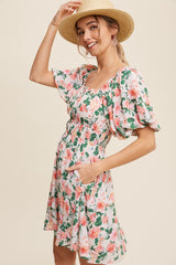 woman wearing a floral short sleeve dress with a cinched waist and pockets, smiling while wearing a straw hat