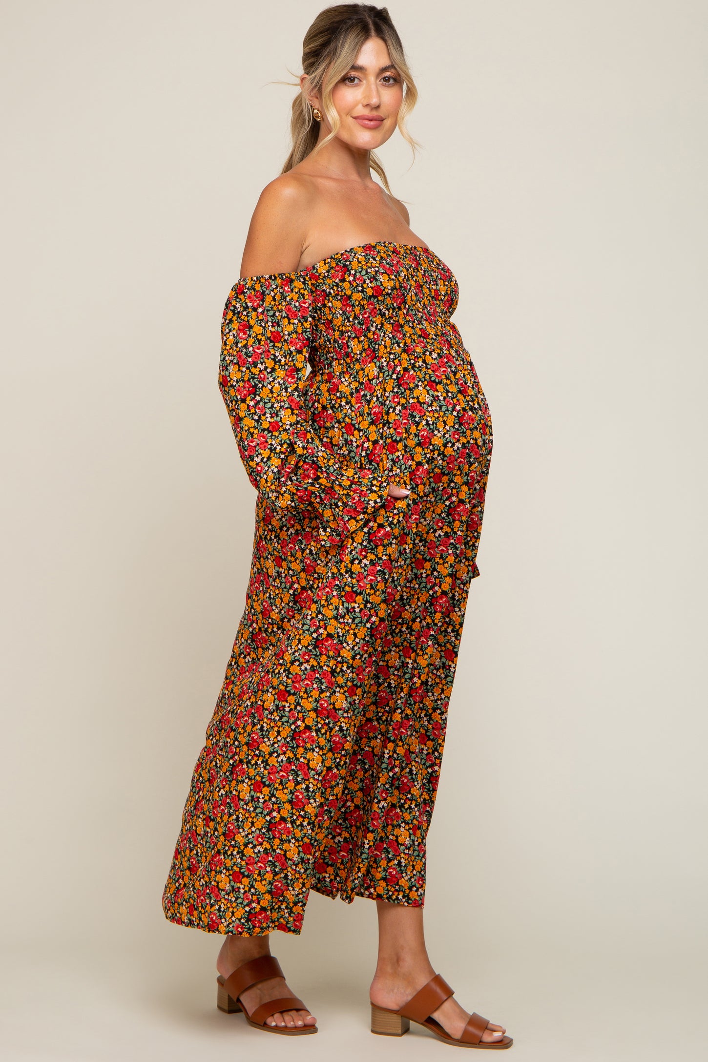 woman wearing a black off-the-shoulder floral maxi dress and showing her baby bump