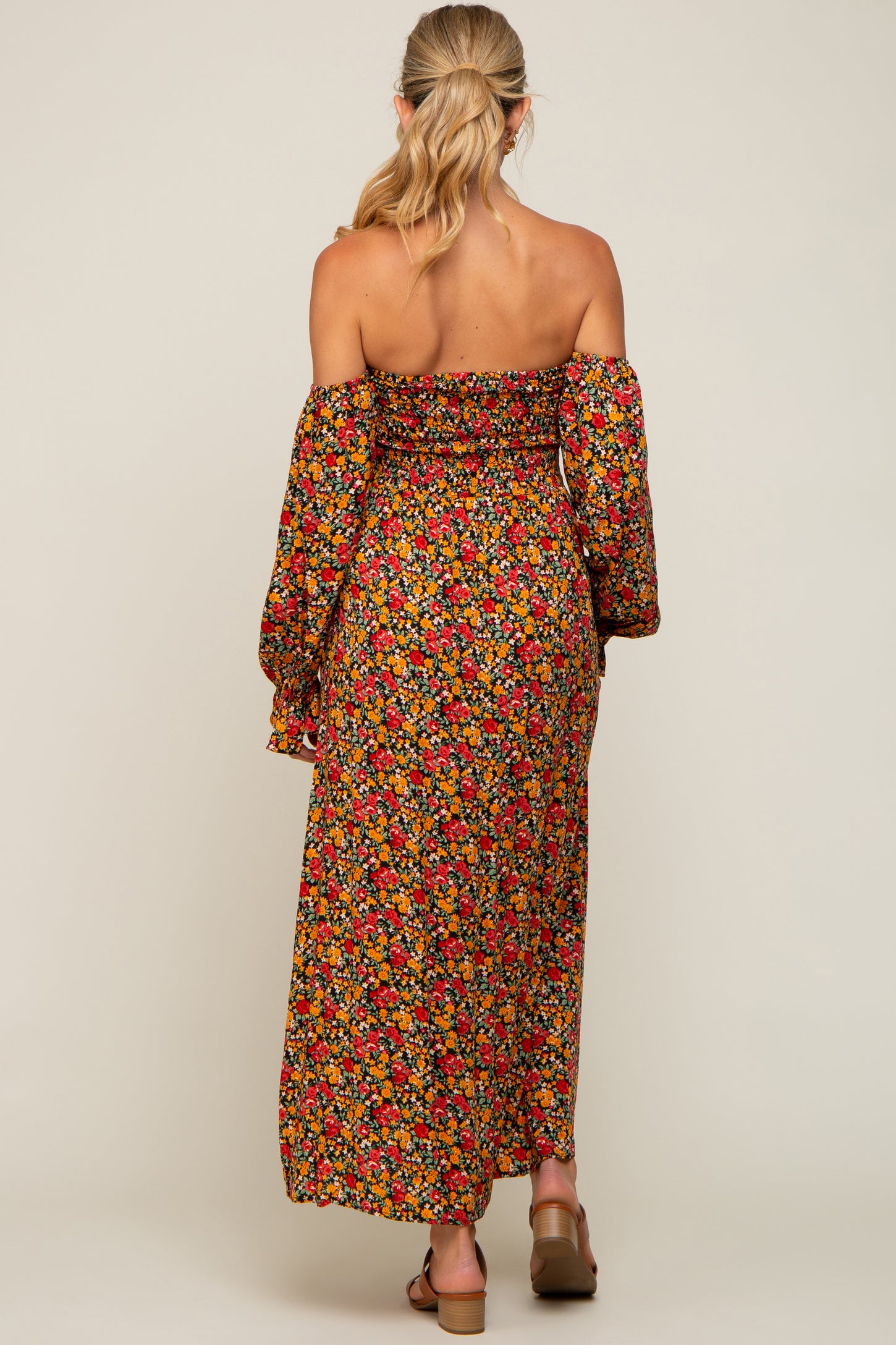 woman wearing a floral off-shoulder maxi maternity dress with long sleeves and a fitted bodice