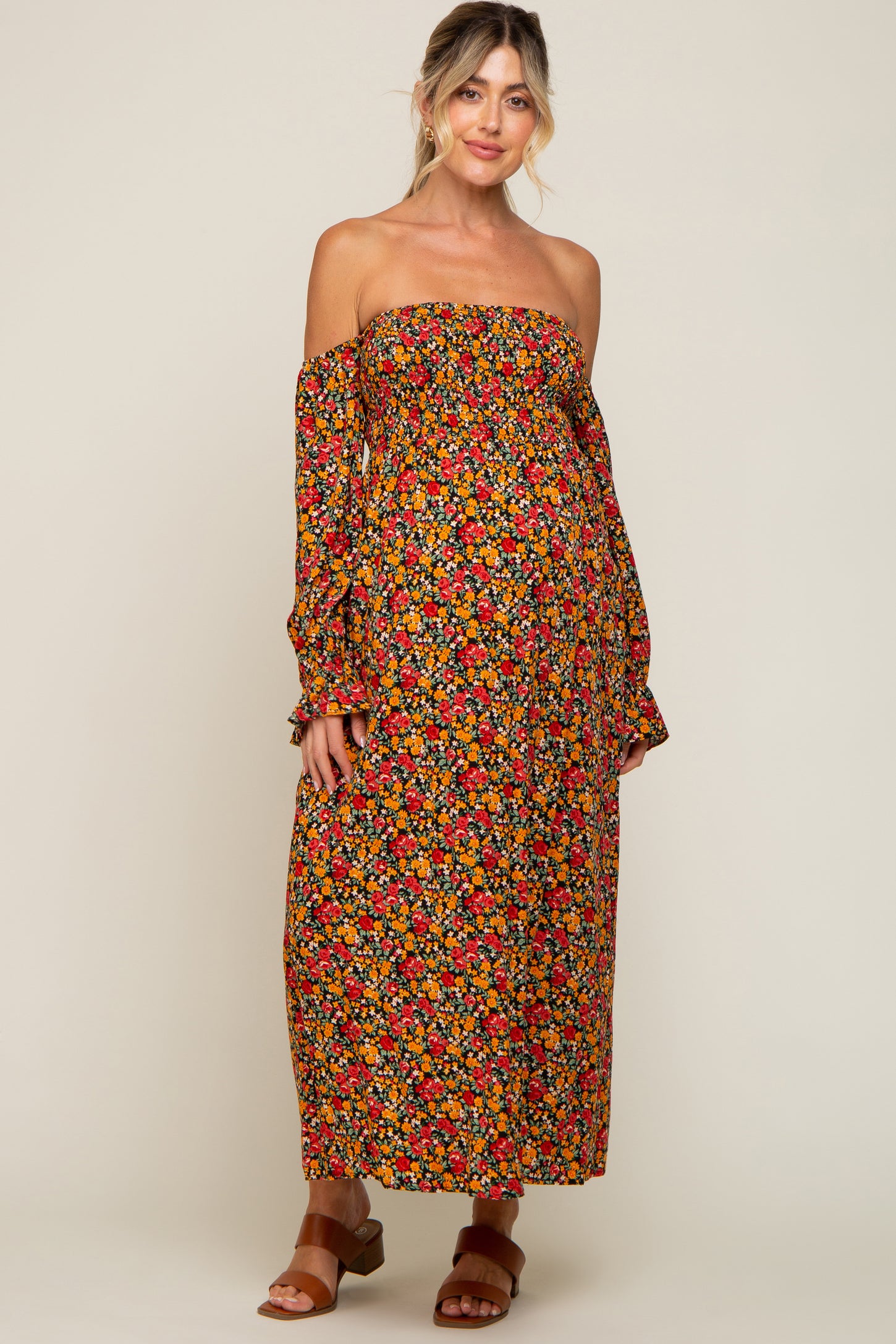 woman wearing a floral off-the-shoulder maternity dress with long sleeves and a visible baby bump