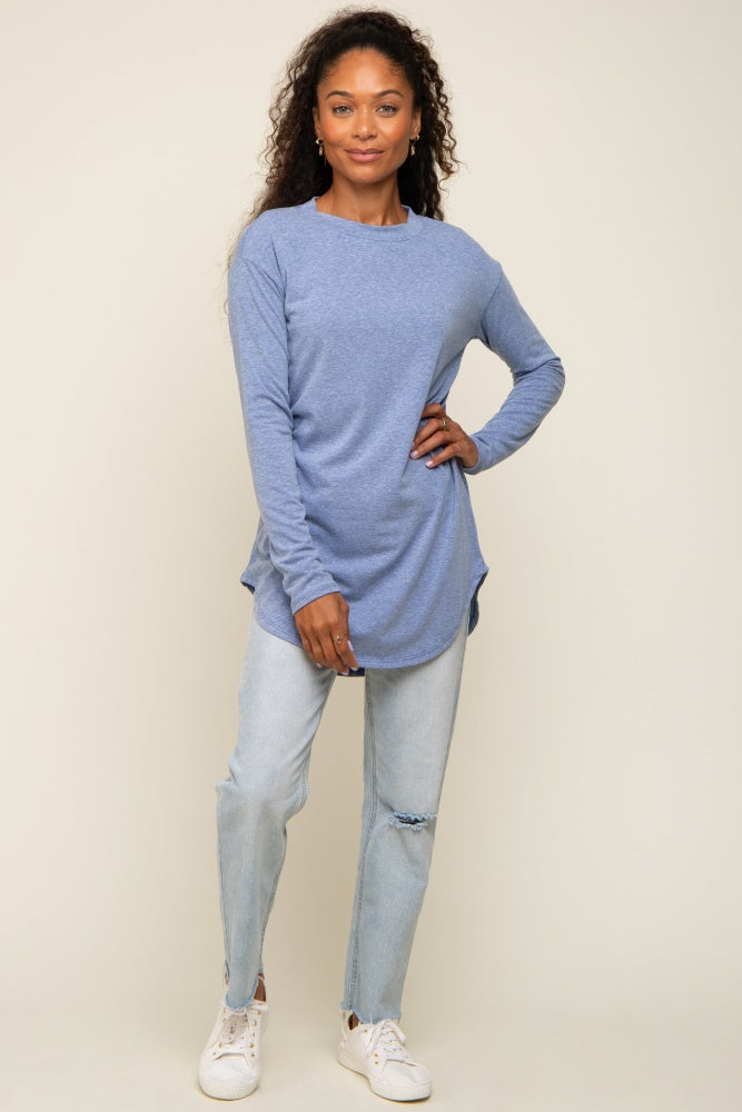 woman wearing a long sleeve light blue tunic top and distressed denim jeans with white sneakers