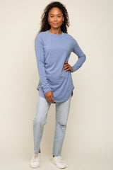 woman wearing a long sleeve light blue tunic top and distressed denim jeans with white sneakers