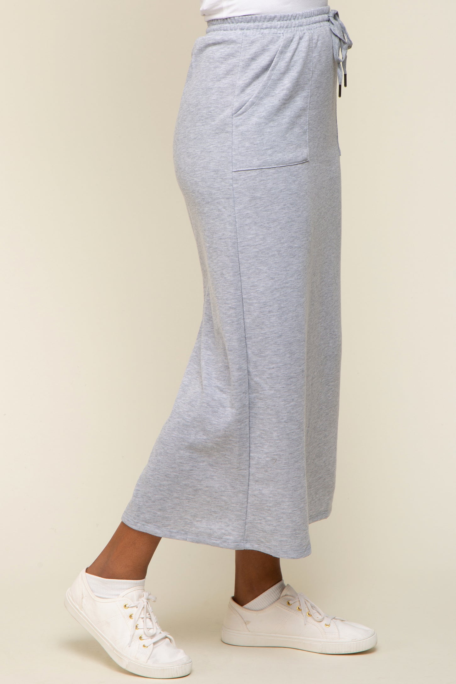 woman wearing a grey midi skirt with pockets and drawstring waist, paired with white sneakers