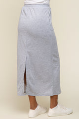woman wearing a light gray maxi skirt with side slits and a casual fit, paired with white sneakers