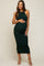 Pregnant woman wearing a dark green ribbed halter neck maternity midi dress and beige heels