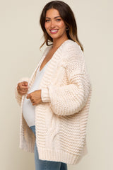 woman wearing a cream chunky knit maternity cardigan and showing her baby bump