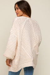 woman wearing a chunky knit cream maternity sweater with a relaxed fit and open stitch details