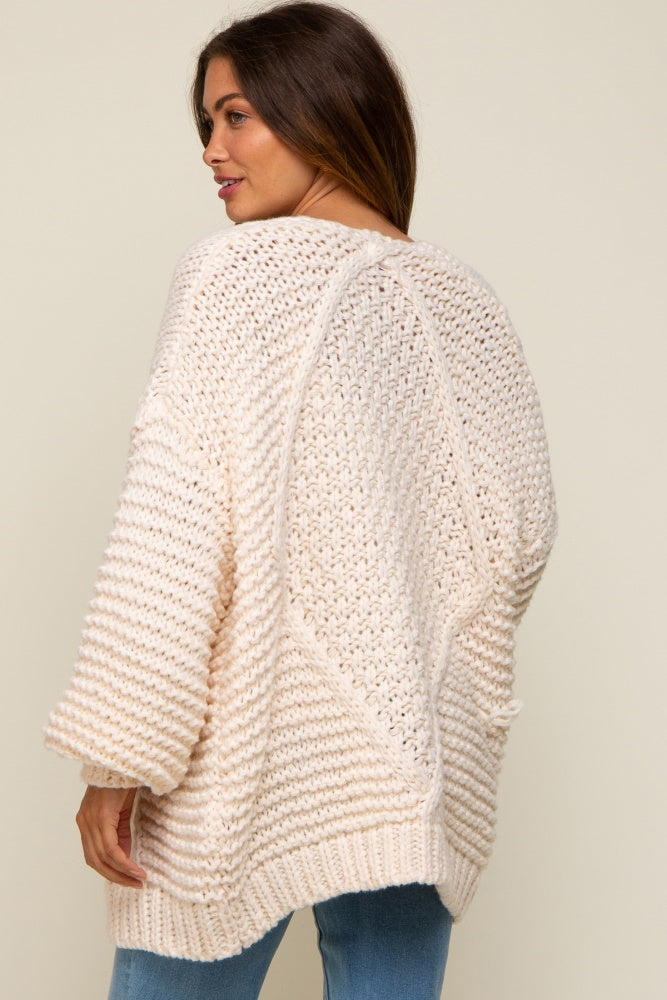 woman wearing a chunky knit cream maternity sweater with a relaxed fit and open stitch details