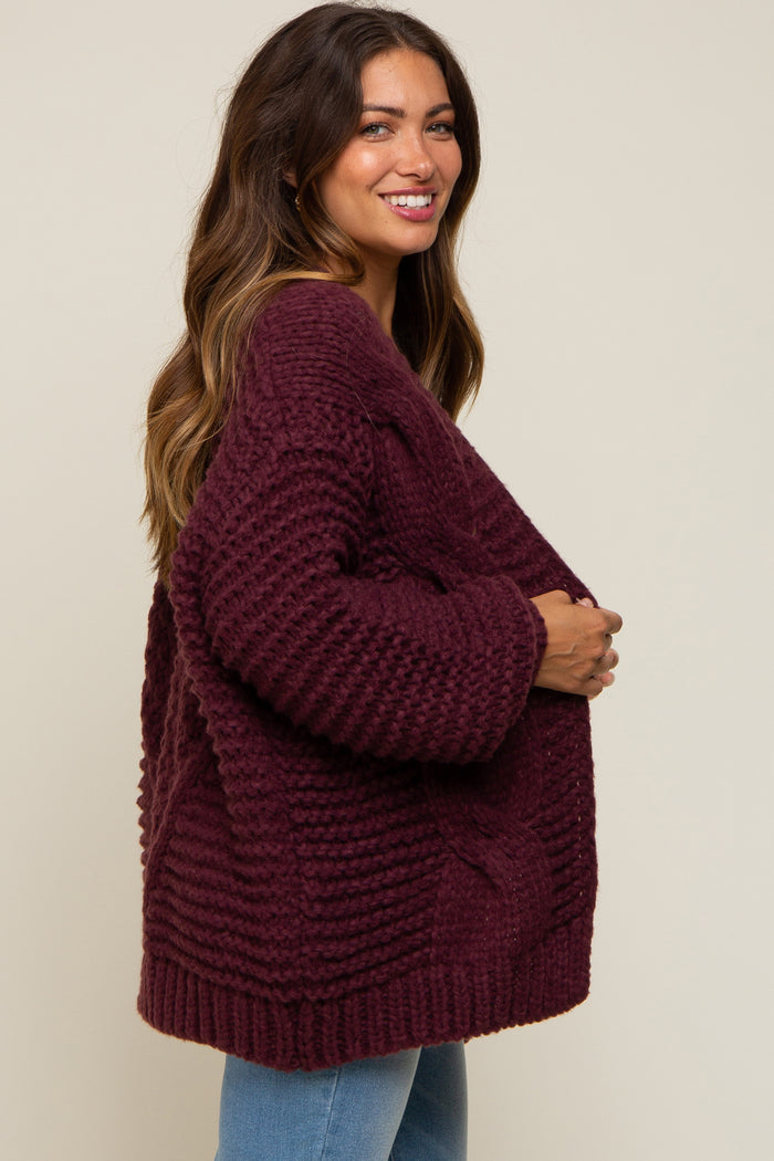 woman wearing a maroon oversized knit maternity cardigan, posed with a visible baby bump
