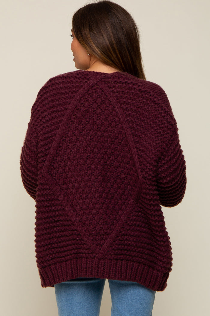 woman wearing a burgundy maternity sweater with a textured design and relaxed fit, featuring a diamond pattern on the back