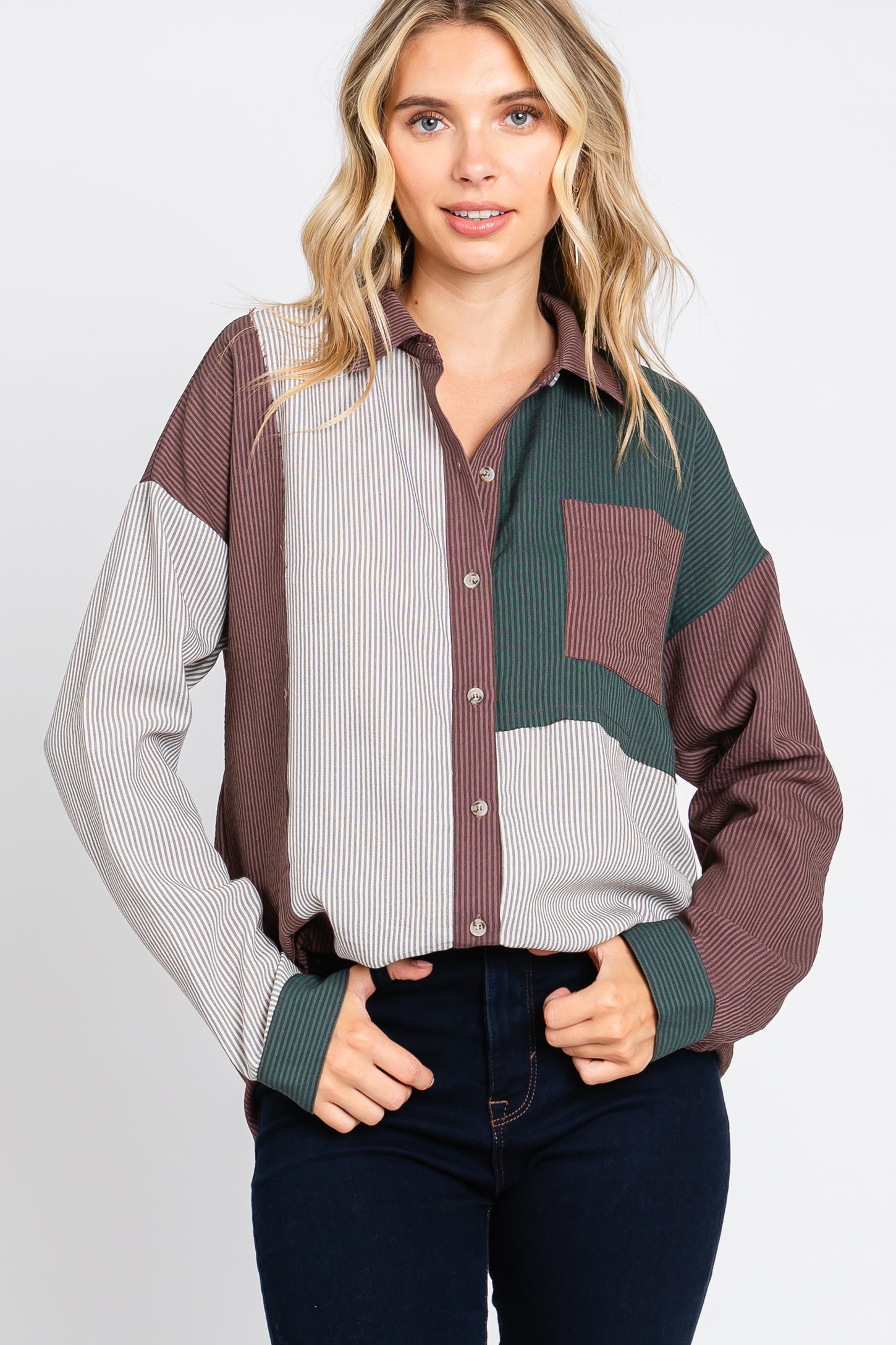 Woman wearing a color block corduroy button-down shirt in brown, green, and striped patterns with dark jeans