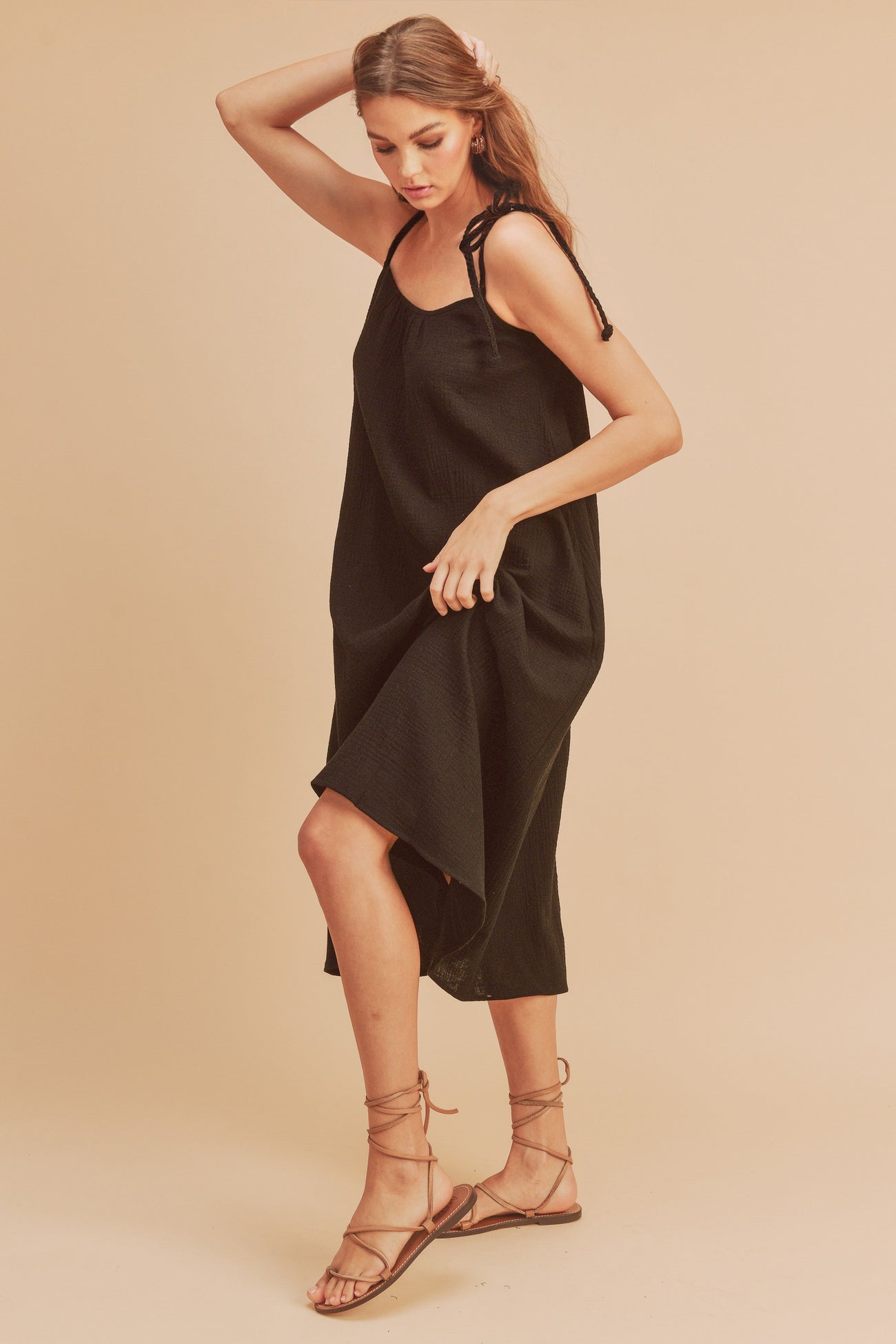 woman wearing a black sleeveless dress with adjustable straps and a flowy silhouette